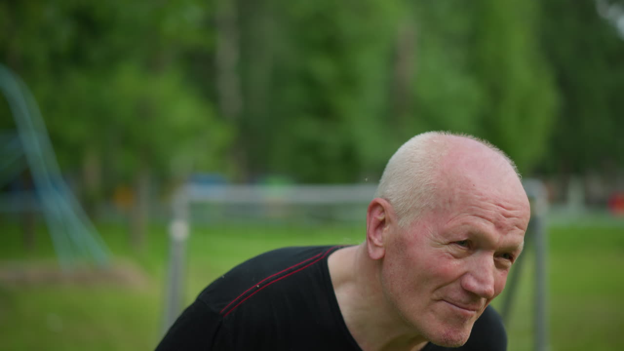 пожилой мужчина умело отводит футбольный мяч, его лицо сосредоточено и решительно, с размытым видом на ворота и травяное поле на заднем плане