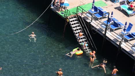 people enjoying swimming and diving off a pier