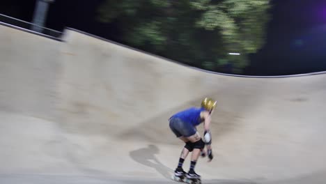 quad skater does a seated drop-in into a bowl and skates back and forth at night