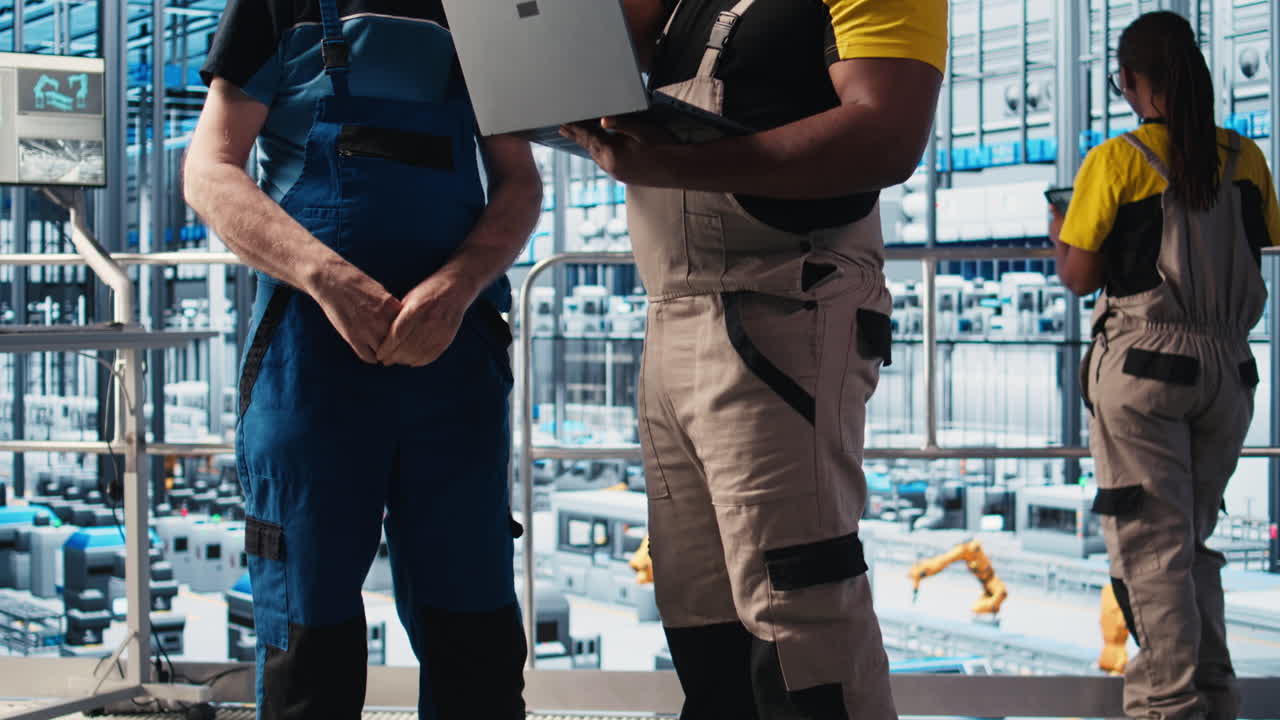 ingeniero sénior de fábrica inteligente enseñando a un nuevo aprendiz a manejar brazos robóticos