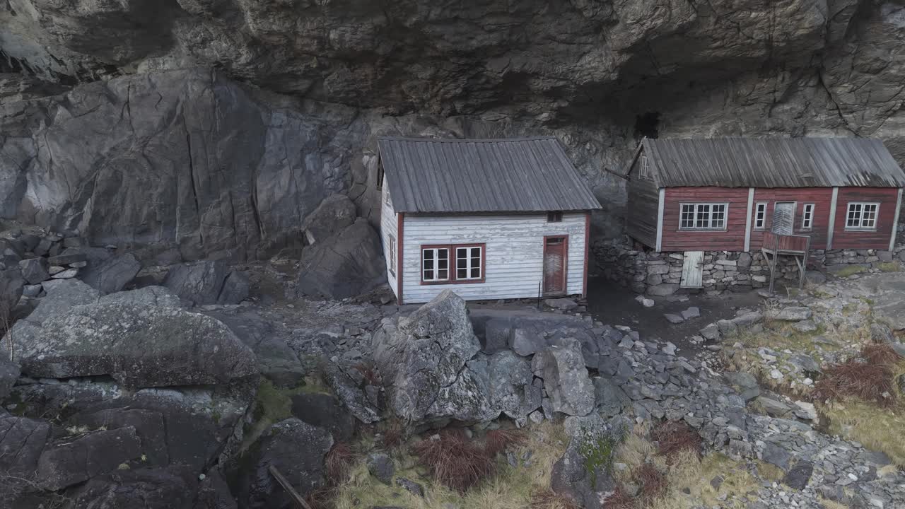 Norveç'teki Helleren tarihi alanı. Kayalıkların altında iki eski ev. Dönen drone çekim görüntüsü
