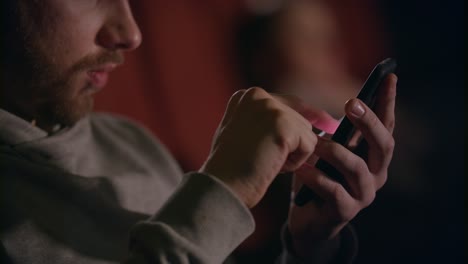 male hands using mobile phone in cinema. man hands scrolling phone at theatre