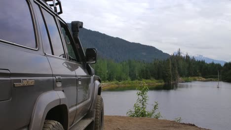 toyota land cruiser parked next mountain lake in canadian wilderness