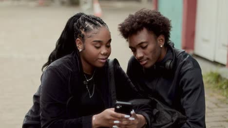 young couple or friends joyfully interacting with a smartphone outdoors