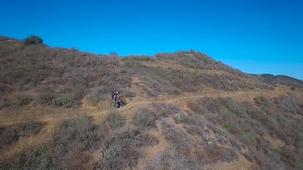 Bella veduta aerea che segue un mountain biker che sale su una montagna californiana 1
