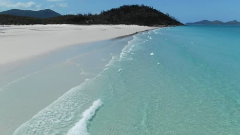 drone volando rápido sobre pequeñas olas y dos personas en la increíble playa white haven de queensland, antena