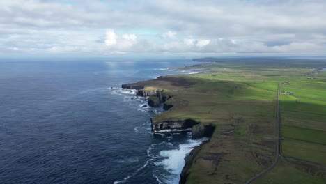 loophead peninsula with dramatic cliffs against the atlantic, lush greenery, and cloudy skies, aerial view