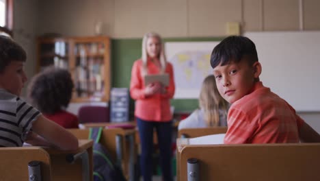 boy smiling while sitting on his desk at school