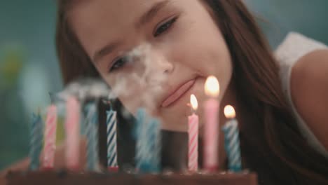 pretty girl blowing candle flame on birthday cake in slow motion. happy birthday