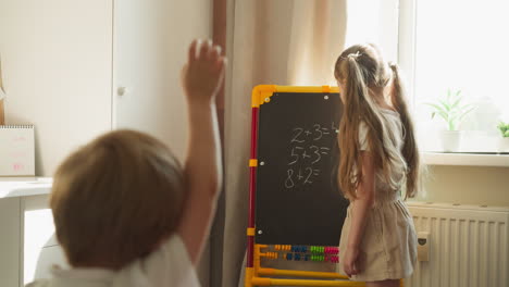 la hermana mayor y el hermano menor juegan la lección de matemáticas en casa