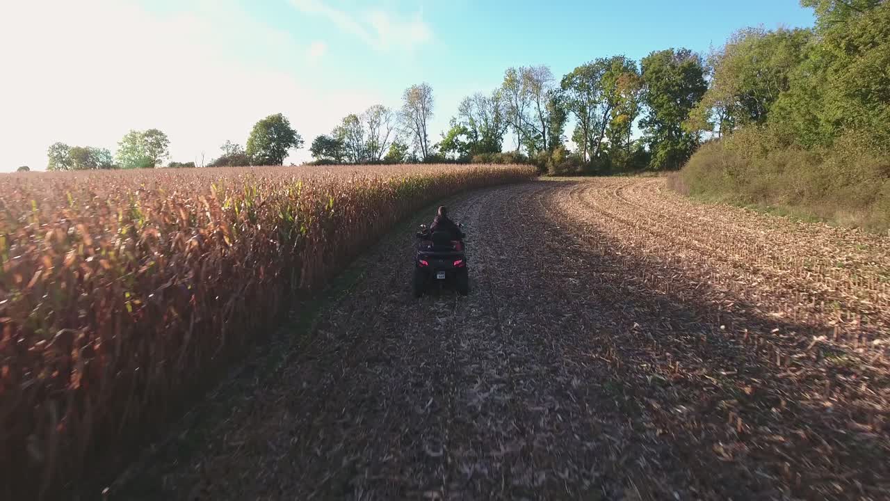 Quad che guida lentamente su un campo in un pomeriggio autunnale soleggiato nella Svezia meridionale, Skåne Österlen, ripresa aerea a bassa quota al seguito.