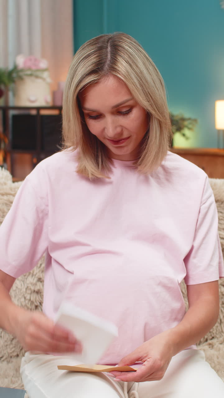 Pregnant woman writing future letter for baby placing envelope on belly smiling hopeful sweet hope
