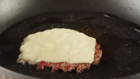 cooking a hamburger with cheese in a pan