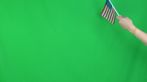 close up of unknown hand holding a waving flag of united states on green screen background in the studio. shot in 4k resolution