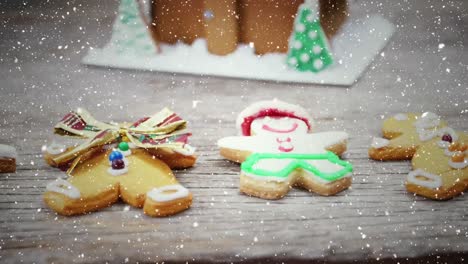 video composition with falling snow over desk with christmas ginger men