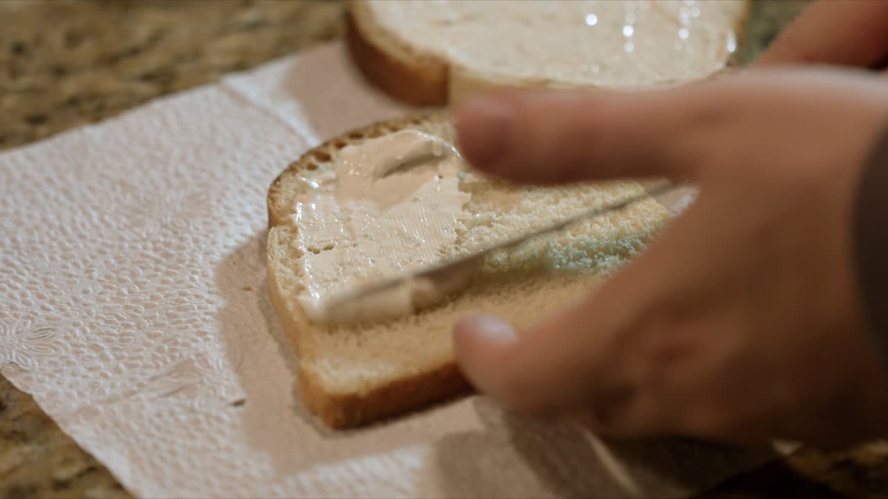 Close up of a male hand spreading cream to a bread slice