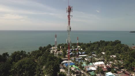 toma aérea de drones ascendentes de la torre de telecomunicaciones en una isla tropical en tailandia con el océano de fondo