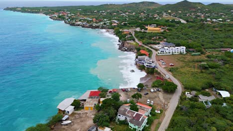 panorámica aérea de la punta oeste de curaçao mientras las fuertes olas del océano agitan la arena en el agua