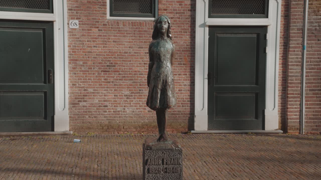 Statue of Anne Frank in front of a brick building