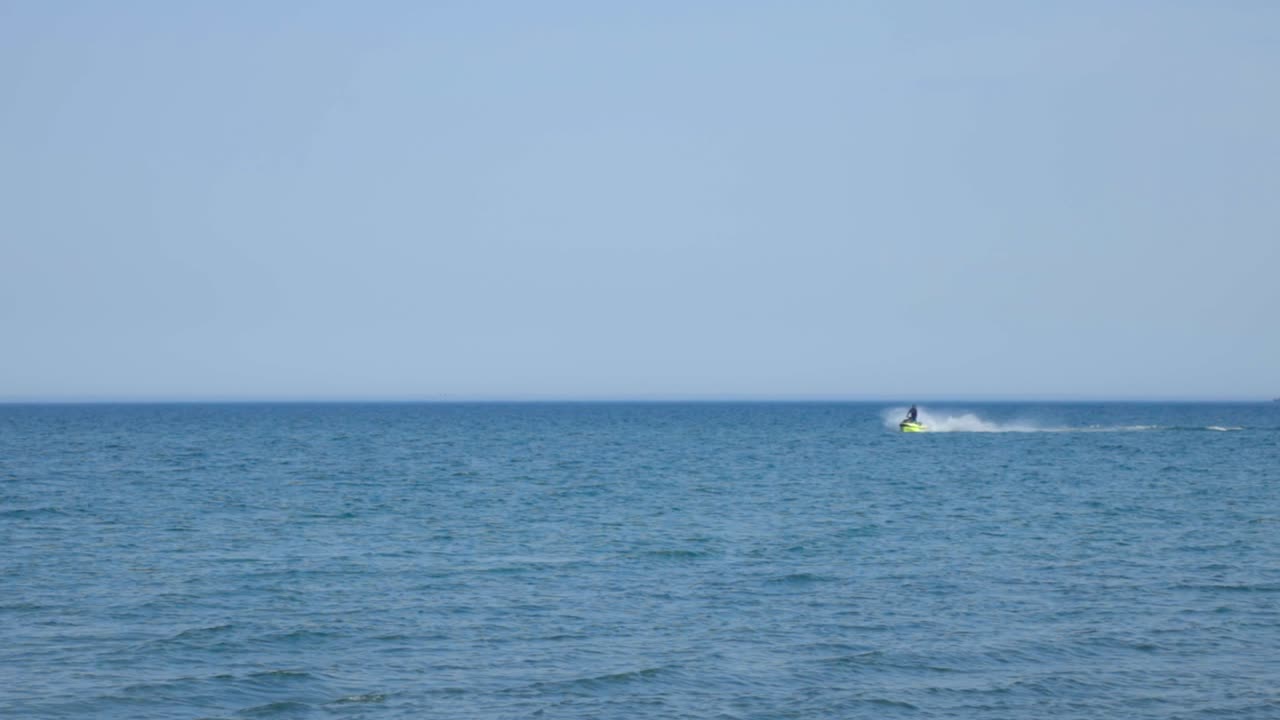 Watersport Activity. A Person Jetskiing On A Tropical Blue Ocean On A Sunny Summer Day. - wide shot