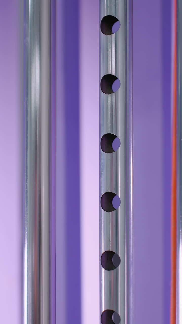 крупный план тяжелой стойки в тренажерном зале, спускаемой на машину сопротивления, подчеркивая контролируемое движение и силовую тренировку, металлические компоненты контрастируют с ярким фиолетовым фоном