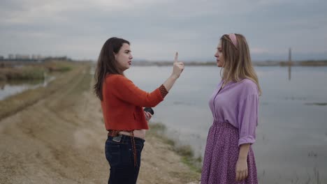 women arguing by a lake