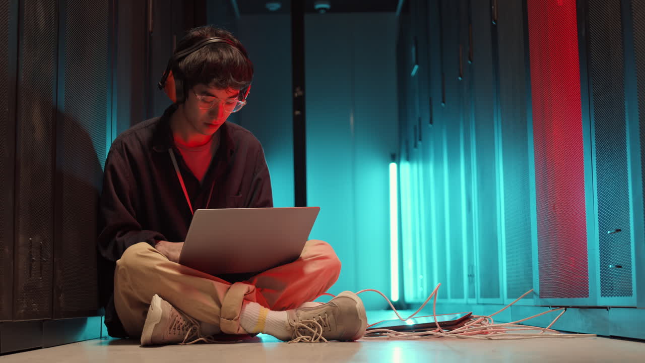 Asian IT Specialist Coding on Laptop in Data Center