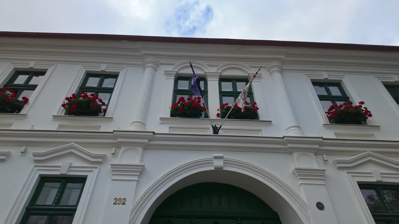 Beautiful white facade with flags and flowers of the Hungarian house called Dunaház on the main street in Torockó, Romania