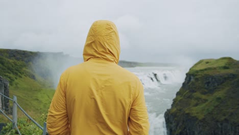 hombre adulto en la cascada gullfoss en islandia en la naturaleza islandesa. turista en impermeable amarillo en la famosa atracción turística y destino histórico en iceland en el círculo dorado.