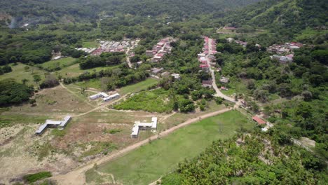 a tropical coastal town nestled between mountains with lush greenery, aerial view