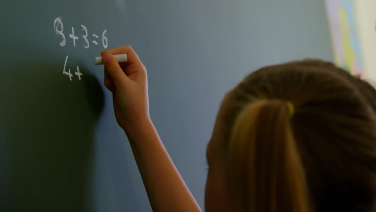 escolar escribiendo en la pizarra con tiza en el aula en la escuela 4k