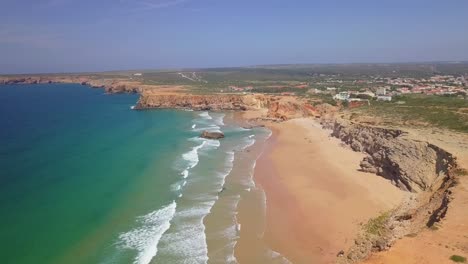 Luftaufnahme-Des-Blauen-Ozeans-In-Sagres,-Algarve,-Portugal-Mit-Großen-Wellen-Für-Surfer