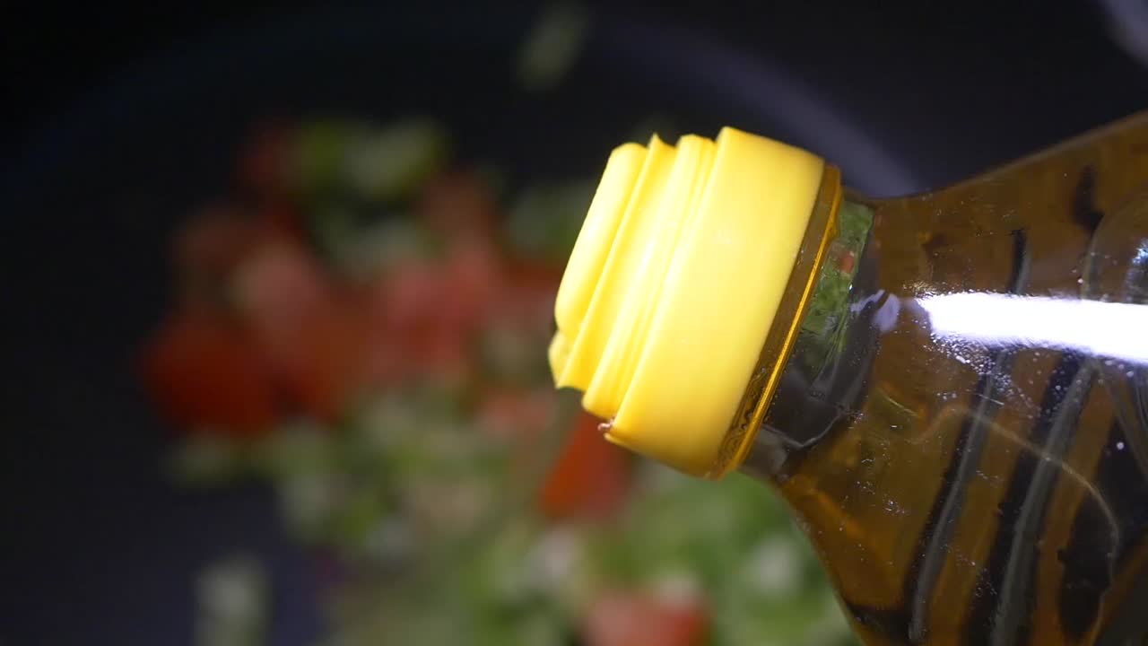 Adding olive oil to a pan of vegetables