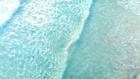 Drohne-Fliegt-Bei-Sonnenuntergang-über-Den-Unberührten-Strand-Von-Son-Saura-Auf-Menorca,-Spanien,-Mit-Einem-Sanften-Schimmer-über-Den-Wellen-Und-Dem-Weißen-Sand