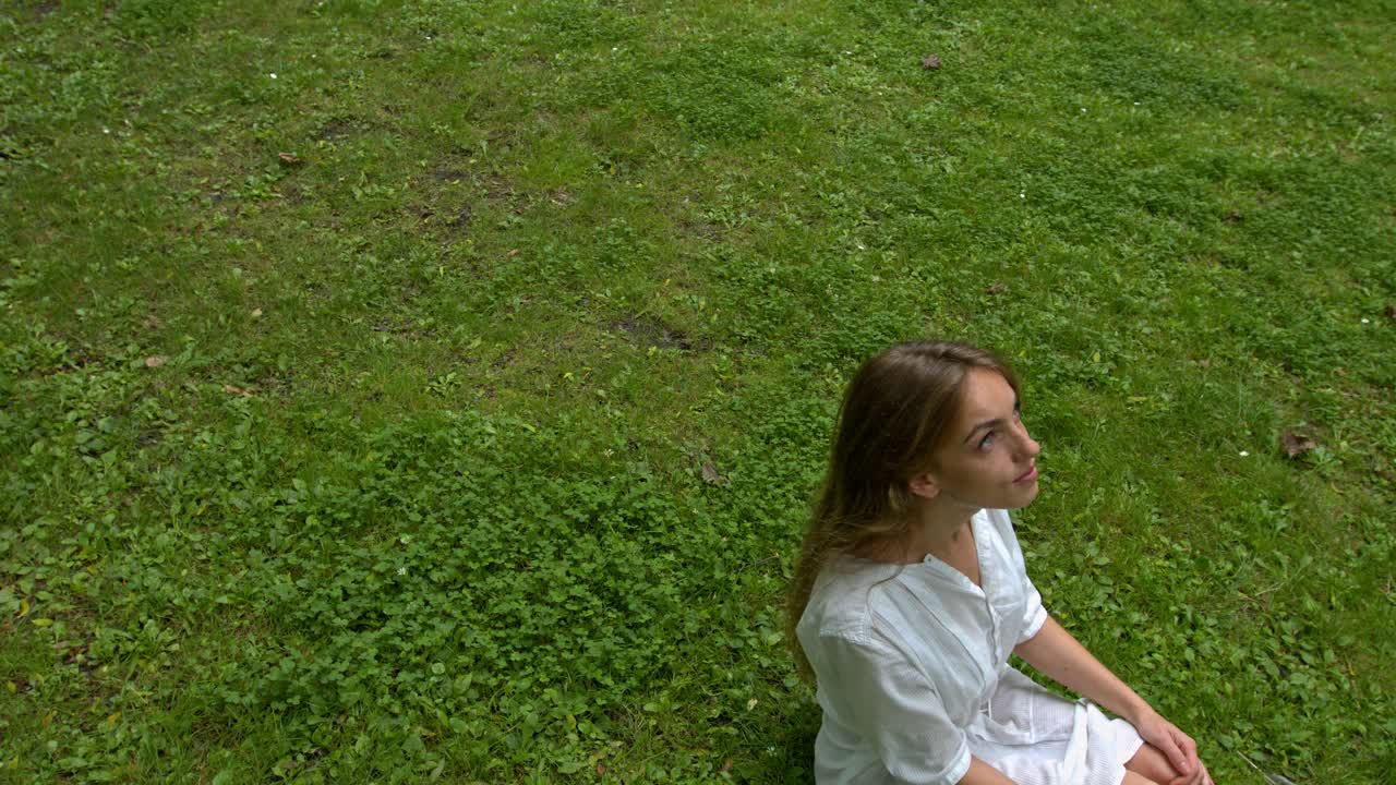 Attractive young woman during a day off in the park lies on the green grass and laughs cheerfully
