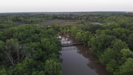 abandoned cox bridge above brown kaskaskia river waters by green trees, patoka, illinois, aerial approach