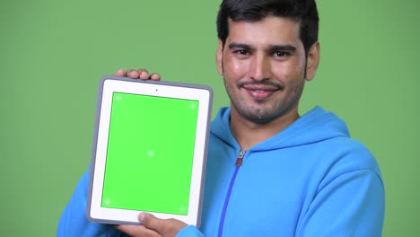 joven persa guapo mostrando la tableta digital