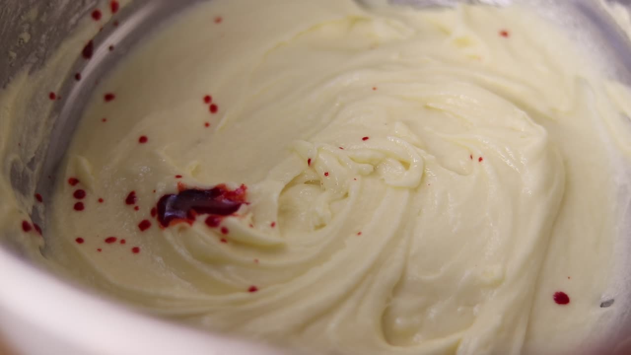 Food coloring being mixed into a creamy batter