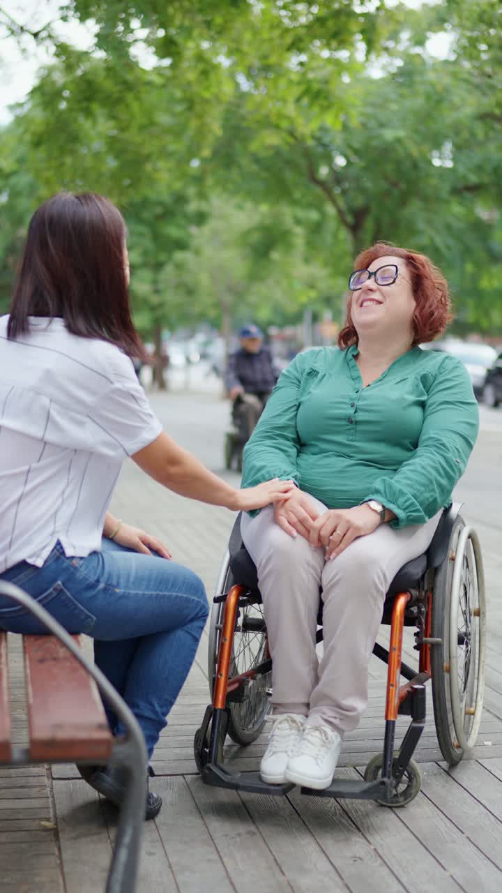 Two women having a conversation outdoors, one in a wheelchair