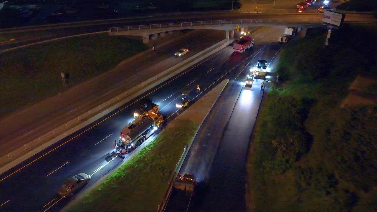 Maquinário pesado pavimentando a estrada à noite. Vista aérea