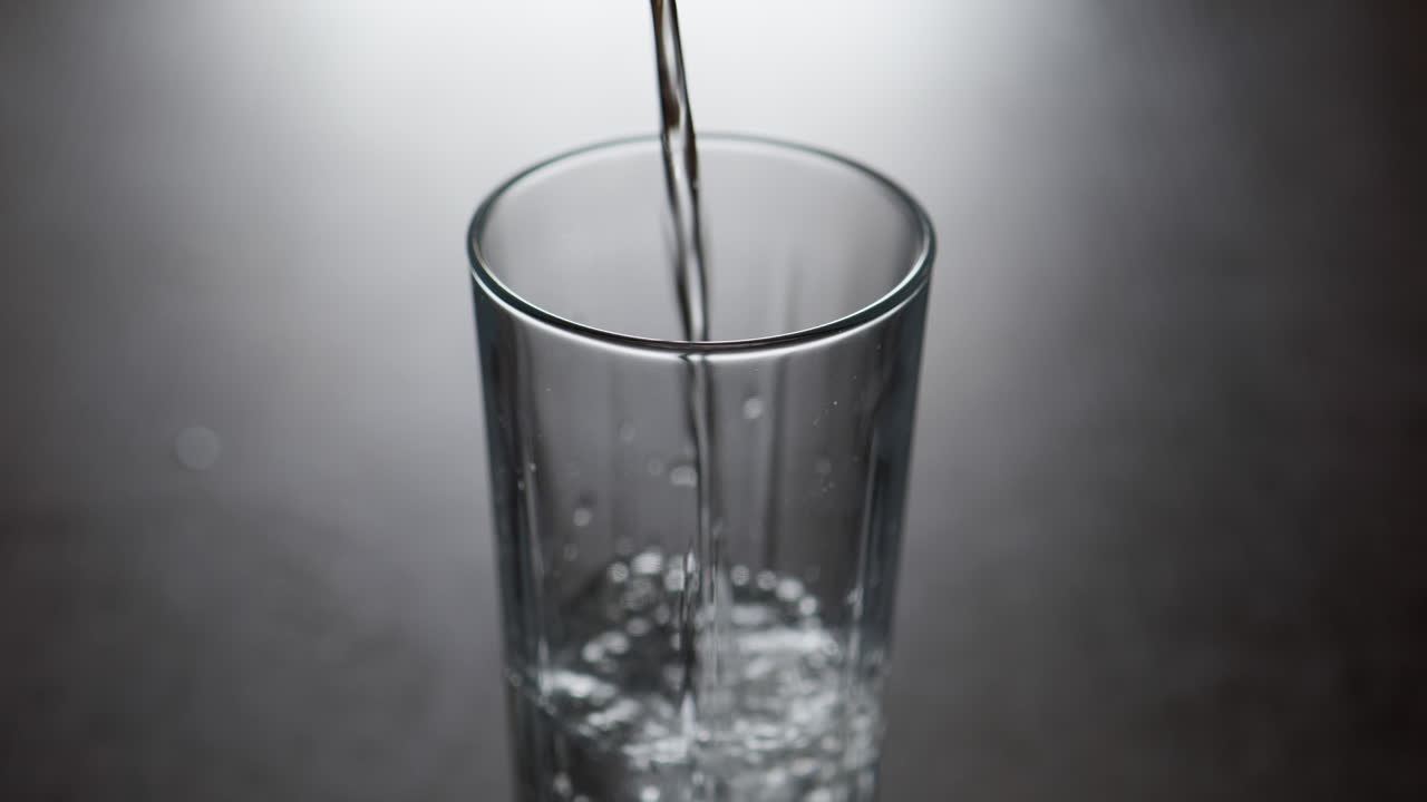 a água fria despeja-se no copo de vidro e cria bolhas de ar em câmara lenta.