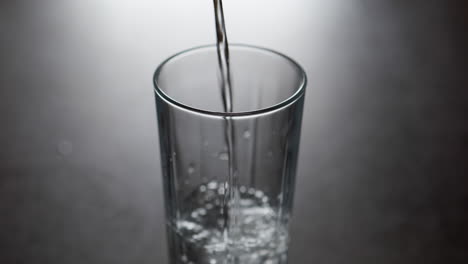 cold water pours into glass tumbler creates air bubbles in slow motion