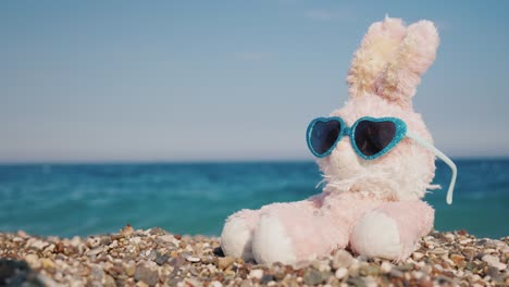 plush rabbit in sunglasses sunbathing on the beach