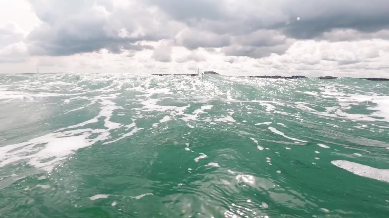 Camera dips beneath the greenish North Sea beside Nieuwpoort, revealing bubbles, foam and waves before resurfacing - Belgian Coast