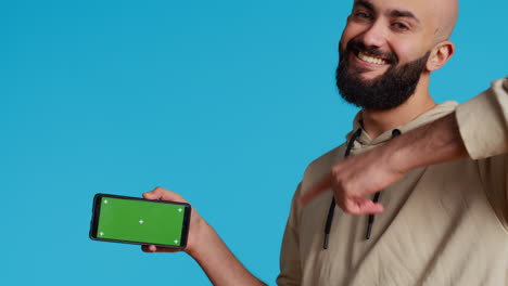 hombre de oriente medio presentando pantalla verde en su teléfono inteligente