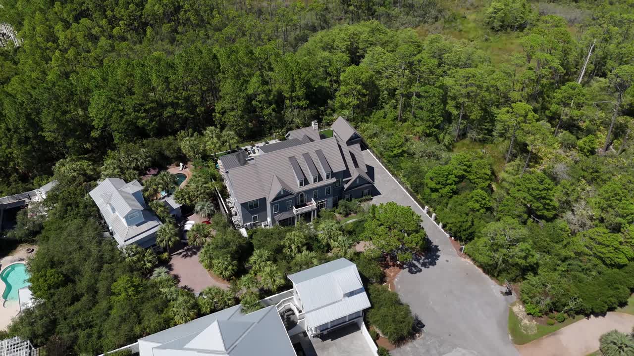 Dynamic spiral drone movement over the secluded luxury home surrounded by forest and greenery environment, 30A, Florida, USA