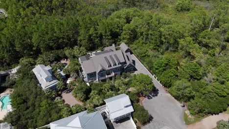 dynamic spiral drone movement over the secluded luxury home surrounded by forest and greenery environment, 30a, florida, usa