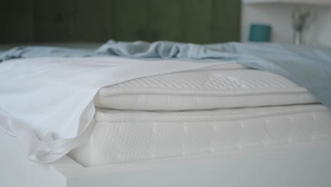 closeup of a white mattress with grey sheets