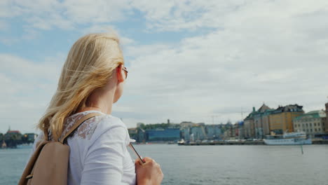 A-Woman-With-A-Pink-Backpack-Admires-A-Beautiful-View-Of-The-City-Of-Stockholm-In-Sweden-Journey-Thr