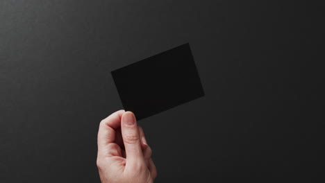 mano de mujer caucásica con tarjeta de visita negra en fondo negro, espacio de copia, cámara lenta